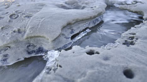 the edges of a sandbank in the ice, through which water flows during the winter, create a unique landscape as the current shapes the ice and sand.