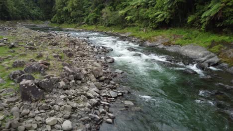 aerial view of pristine forest river flowing over boulders down rapids