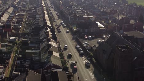 Luftaufnahme-Umkreist-Reihen-Historischer-Reihenhäuser-Mit-Einer-Langen-Straße,-Die-Bei-Sonnenaufgang-Zum-Geschäftigen-Stadtzentrum-Führt