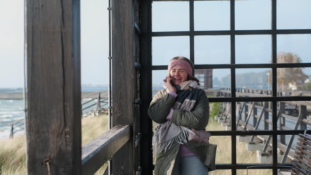 Frau telefoniert an einer Strandhütte