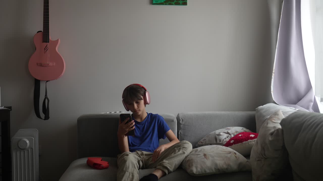 Boy with Headphones Listening to Music on Smartphone