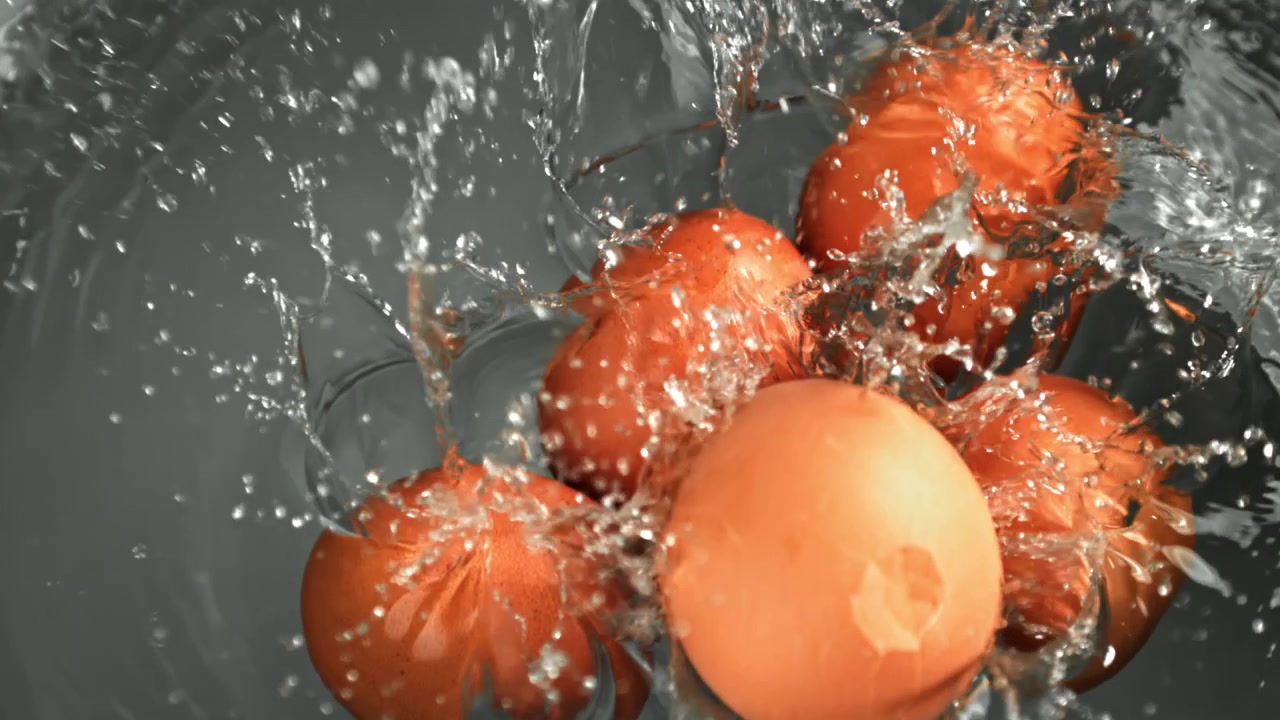 Movimento rallentato di uova marroni che schizzano nell'acqua.