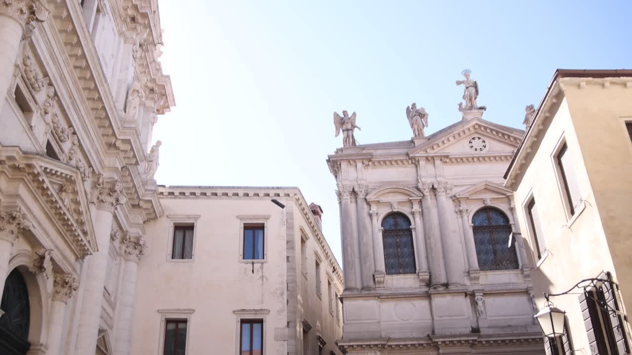 Close-up view of Venetian buildings with statues, ornate facades, and Corinthian columns.