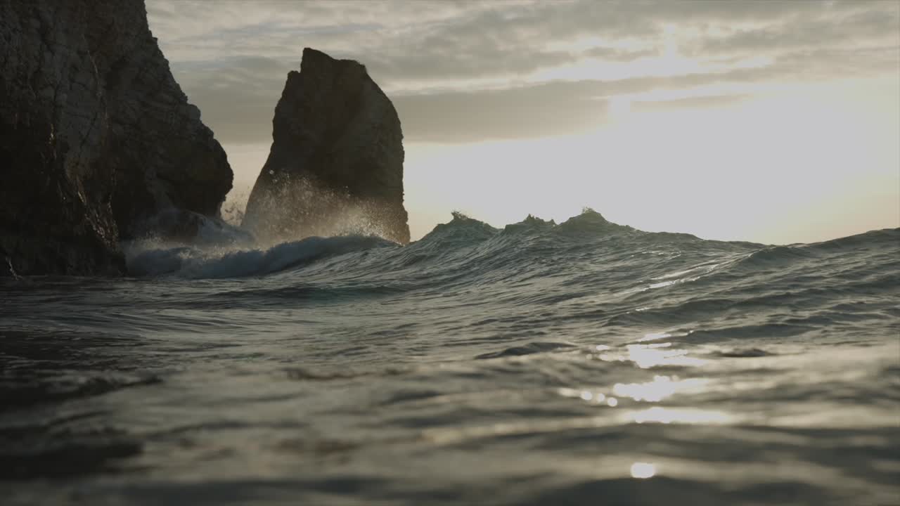 olas chocando contra las rocas en la hora dorada