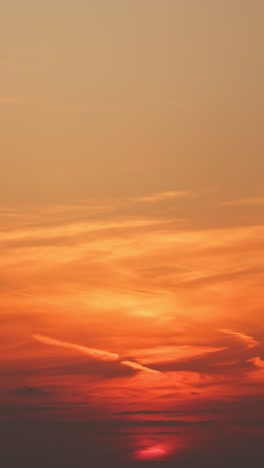 slow vertical shot of a vivid sunset descending over a calm sea