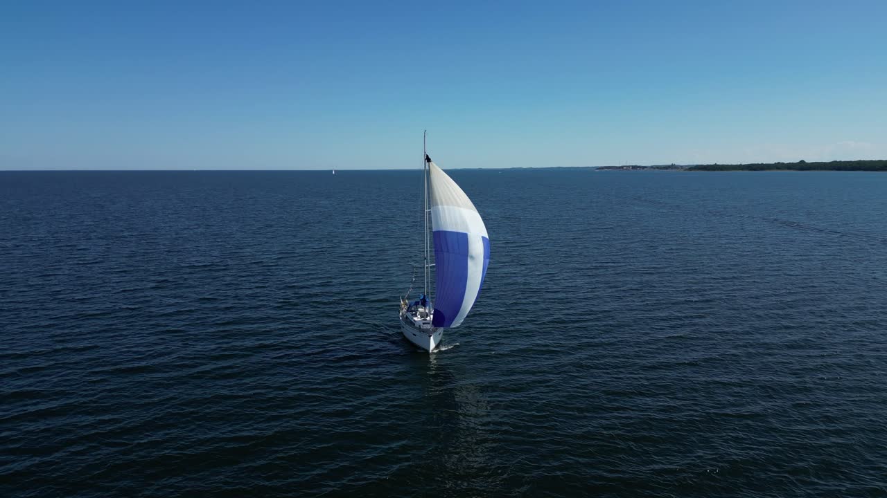 un velero navega con gracia por el mar báltico con una colorida vela gennaker, ofreciendo una experiencia pacífica y tranquila