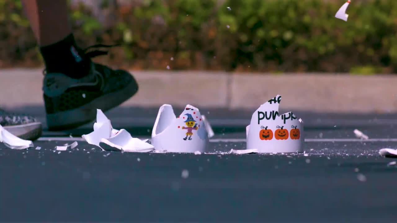 Ceramic white coffee or tea mugs being crushed to pieces and broken by a steel or metal golf bat or stick on slow motion during the summer time. Pieces and shards of ceramic fly everywhere in the sun.