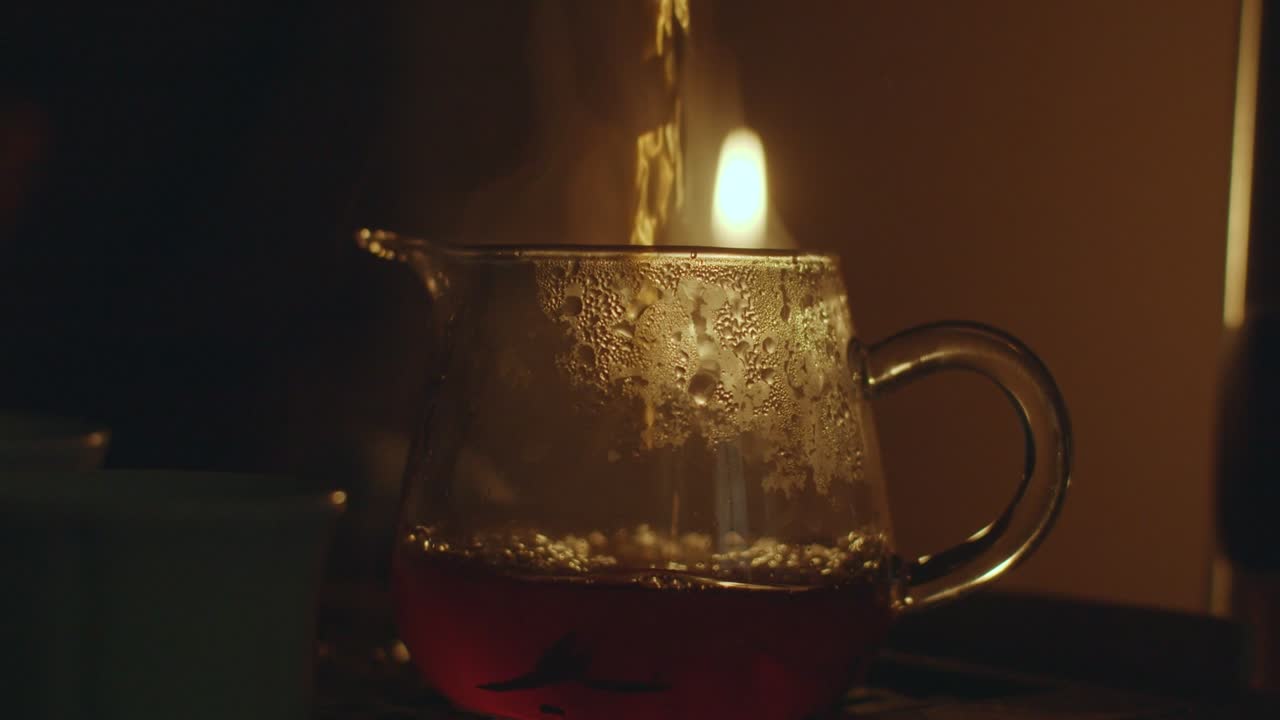 유리 항아리에 는 뜨거운 차의 클로즈업, 얼굴 없는 사람이 유기적인 중국 차로 투명한 차병을 채우는 느린 동작.