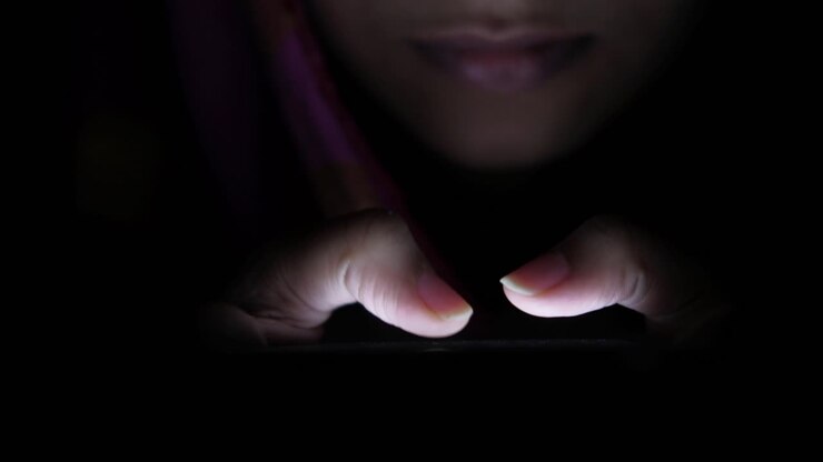 Donna che utilizza il telefono cellulare di notte