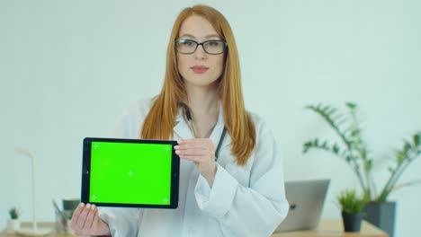 doctora con gafas que demuestra una tableta digital con llave de croma en el hospital, retrato de una mujer con túnica blanca con estetoscopio en el consultorio médico que muestra una tableta virtual con pantalla verde.