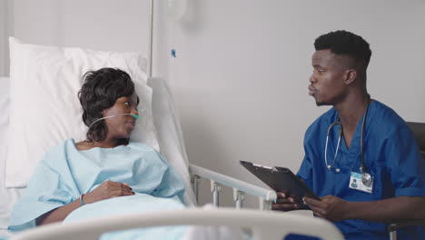 a young african-american male doctor is talking to a patient. a black woman patient talks to a doctor