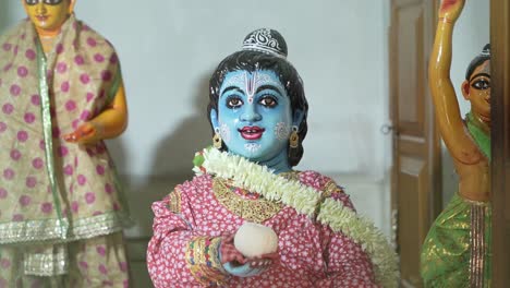 a childhood statue of the hindu deity lord krishna in which he is known as gopala and is holding a laddu