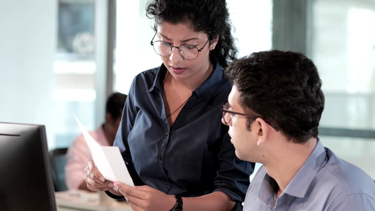 un jefe femenino joven y decepcionado con gafas regañando y gritando a un joven empleado masculino o subordinado sentado frente a una pantalla de computadora