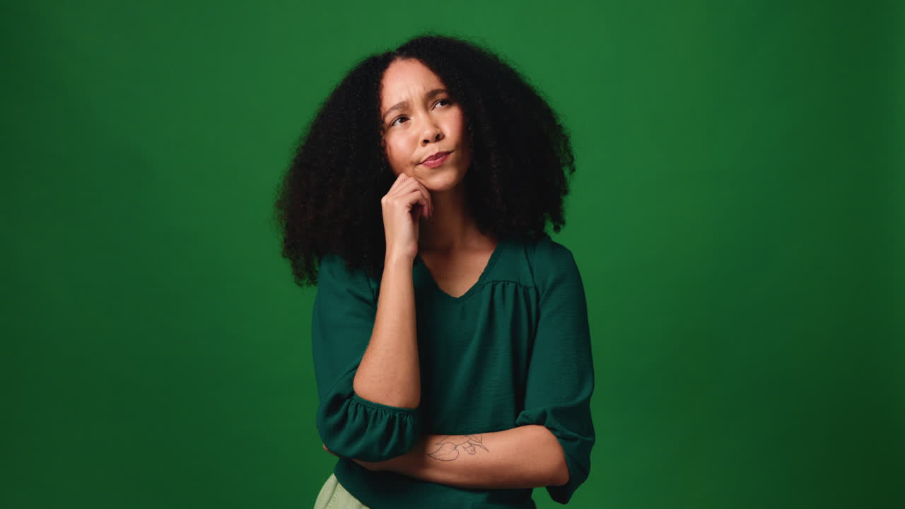 A woman thinking in front of a green screen
