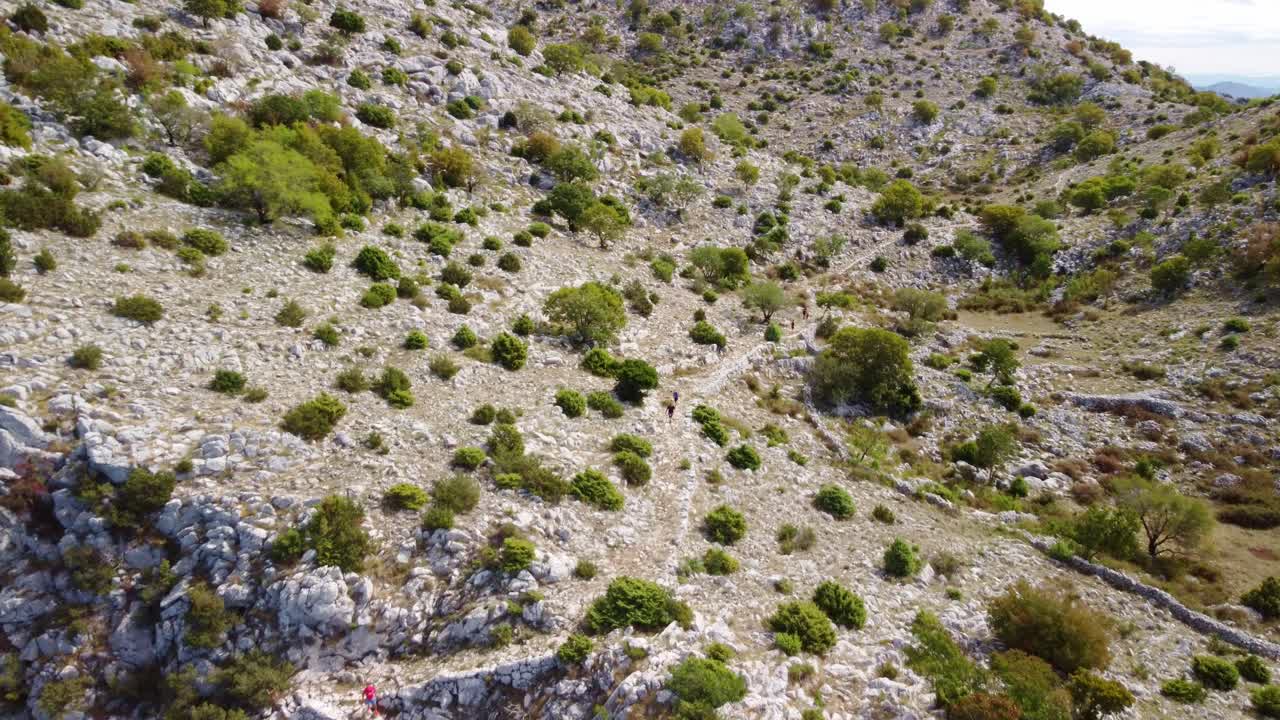 Hikers trekking rocky trails of Mount St. Ilija, Croatia, aerial view with expansive scenic landscapes