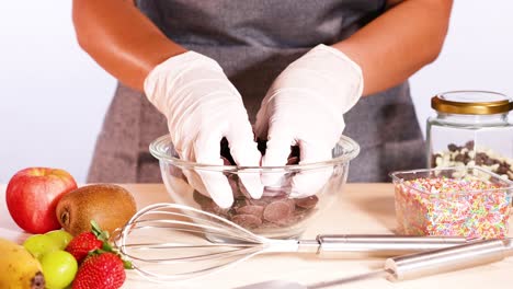 hands arranging chocolate discs in a bowl