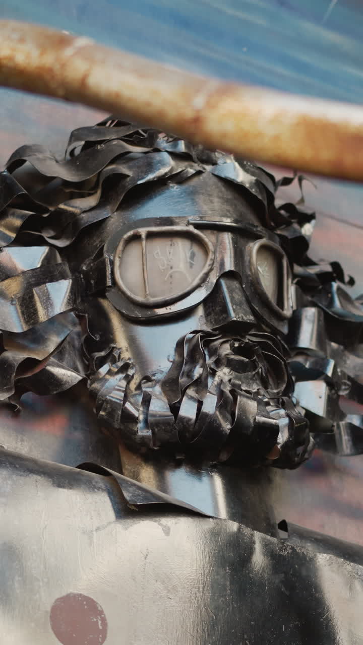 primer plano de máscara de black metal con gafas, pelo de metal triturado y barba soldada en pared urbana, sombra intensa y detalles de óxido que crean una inquietante sensación de guardián, presencia similar a una instalación en callejón, retrato