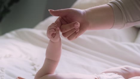 detail of baby holding finger of the mother