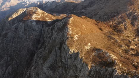 drone flyover on rocky mountains and escarpments of kotor bay, montenegro, on late afternoon