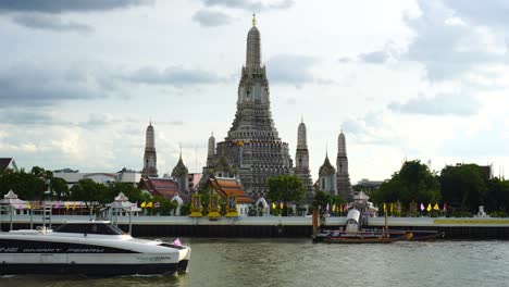 A-passenger-ferry-motors-past-the-Wat-Arun-Ratchawararam-Ratchawaramahawihan,-Temple-of-Dawn