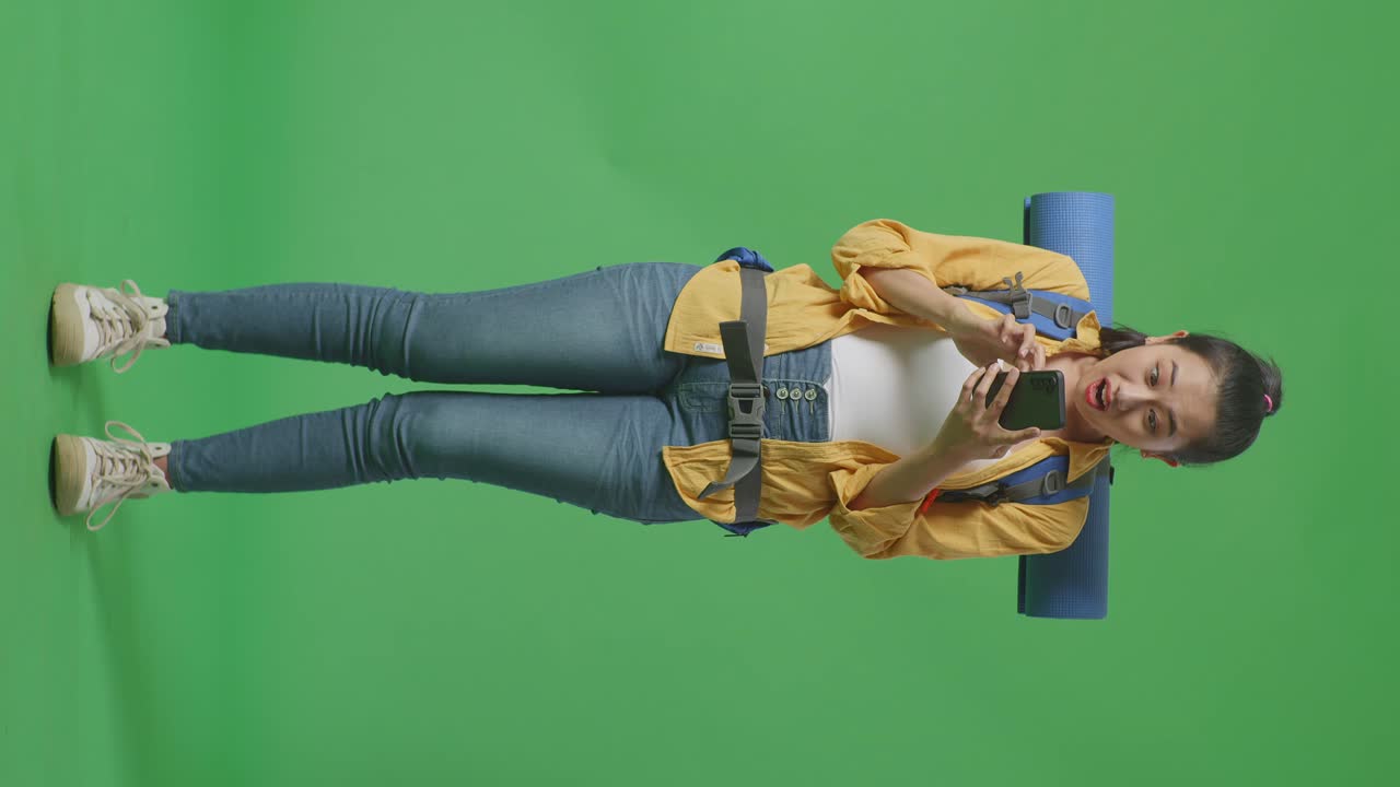 mujer tomando selfies con mochila y estera de yoga