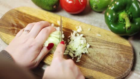 Dicing-white-onion-on-chopping-board-with-veggies-around