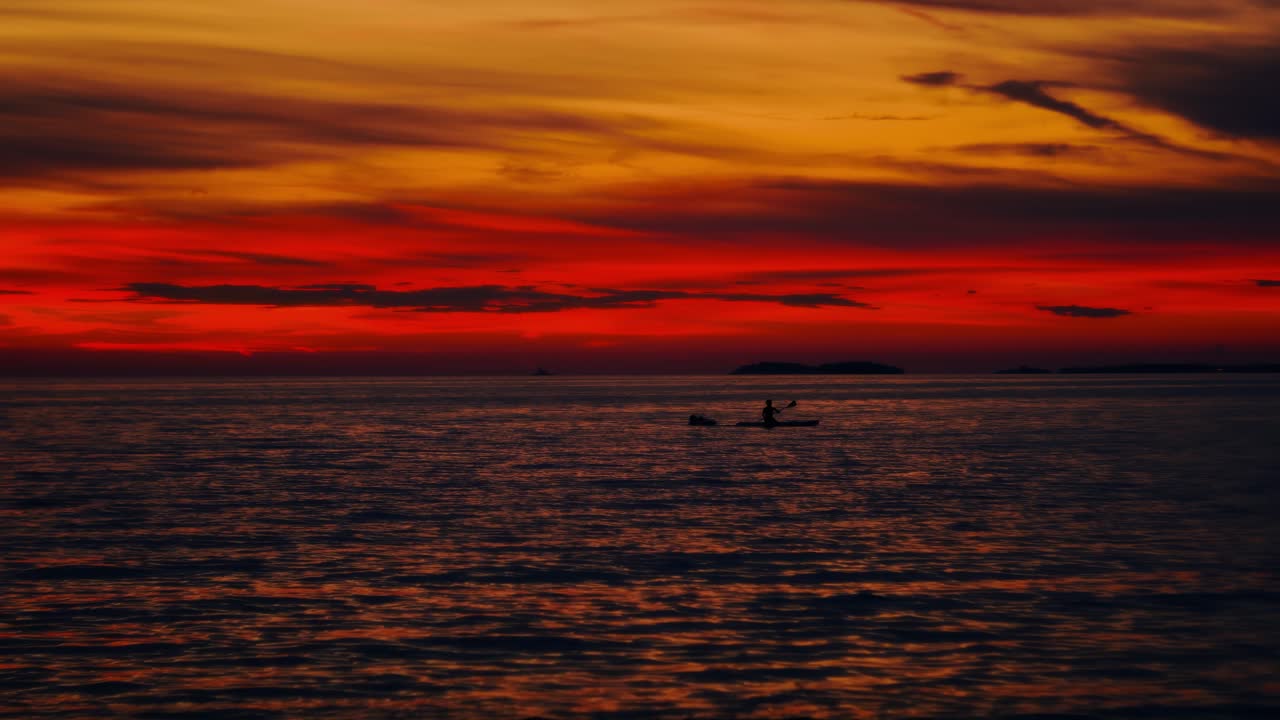 Sunset SUP paddle scene at the coast of Istria Croatia with colorful sky and calm seaside water