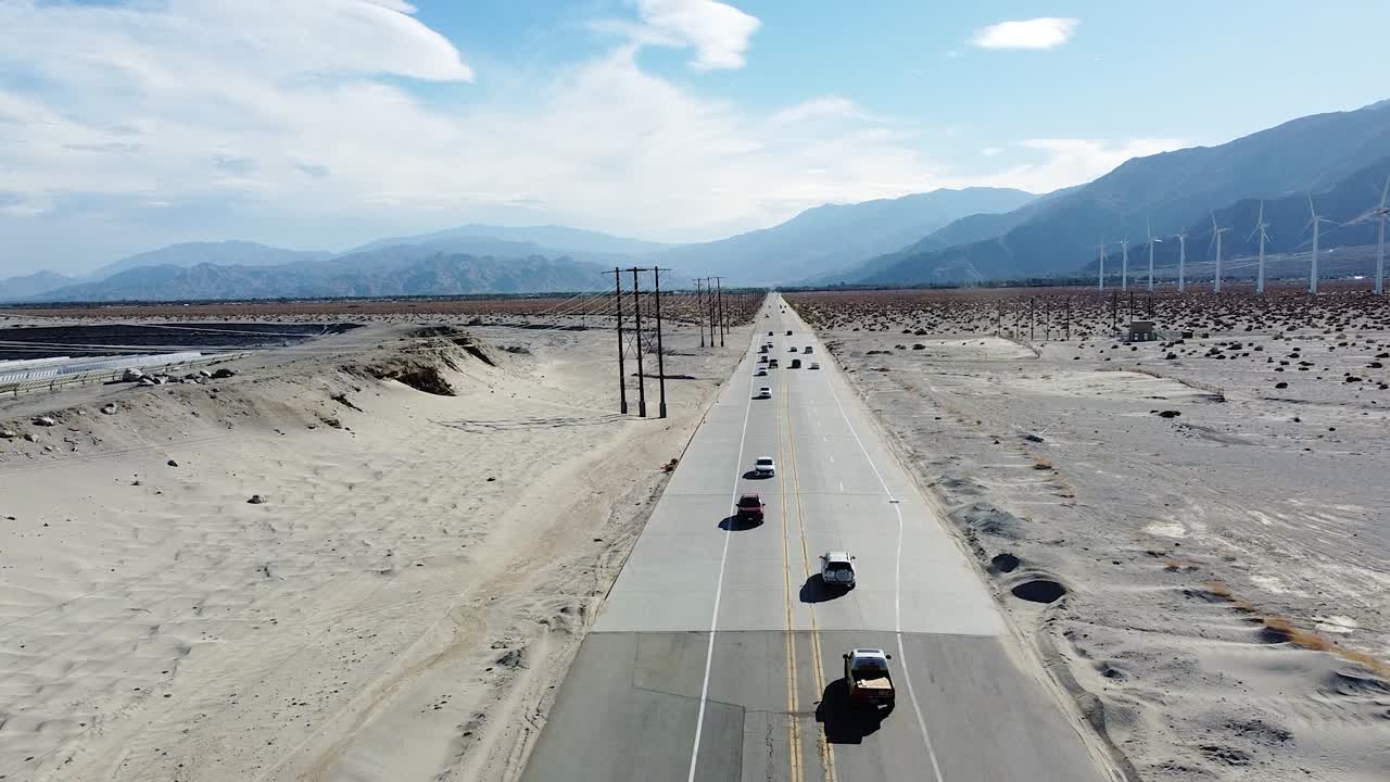미국 사막 지역의 풍력 터빈 농장과 바쁜 고속도로, 공중 드론 보기