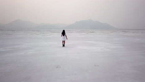 Dramatic-aerial-of-woman-in-dress-walking-in-Utah-desert-salt-flat