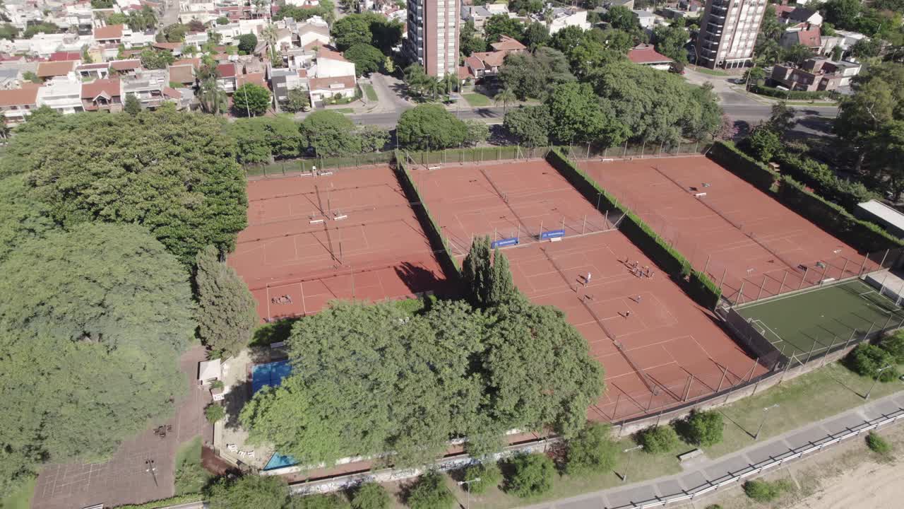 Vista aerea di un complesso tennistico in città, con un rigoglioso boschetto di alberi