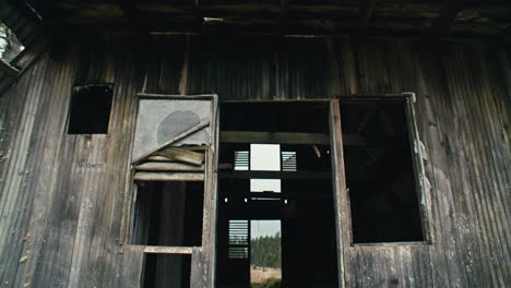 Cabaña-De-Troncos-Triangular-Con-Techo-De-Zinc-Abandonada-En-Un-Campo-De-Hierba-Serrada-Y-Pinos-Caribeños-En-Las-Montañas-Con-Cielo-Nublado