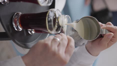 el barista usa una cuchara para disminuir el flujo y la propagación de la crema o la leche en el café oscuro en vaso