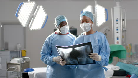 african american male and female surgeons looking at x-ray scans in operating theatre, slow motion