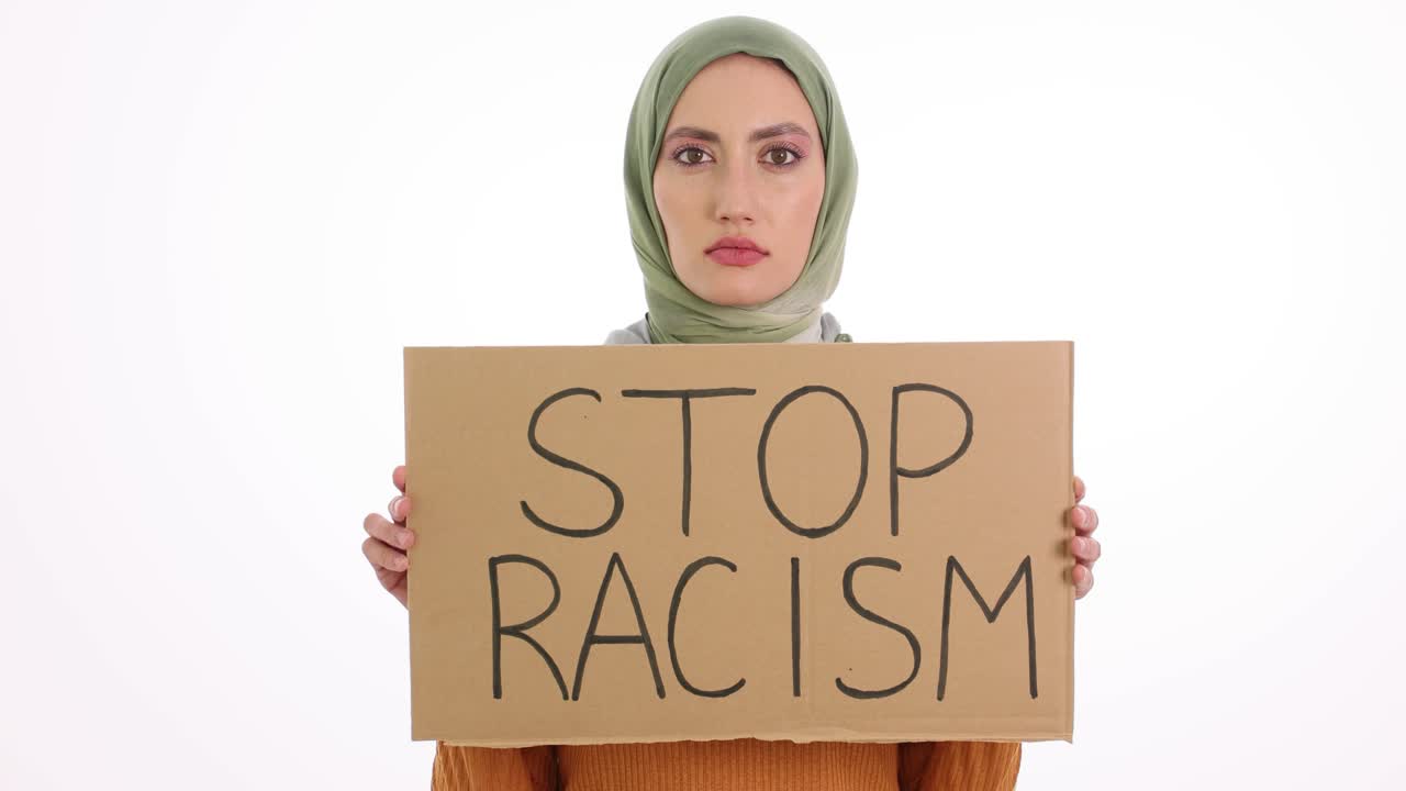 Woman in hijab holding a 'STOP RACISM' sign