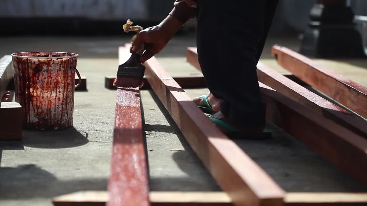 Un falegname sta verniciando del legno. Primo piano.