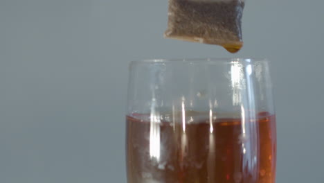 Tea-bag-being-put-in-and-taken-out-of-glass-of-water---close---60-fps