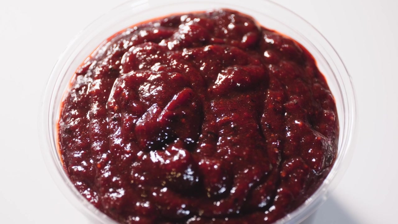 Filmato di cucina ravvicinato che mostra un primo piano di salsa chamoy in un contenitore di plastica durante la preparazione di una ricetta casalinga di salsa chamoy da zero