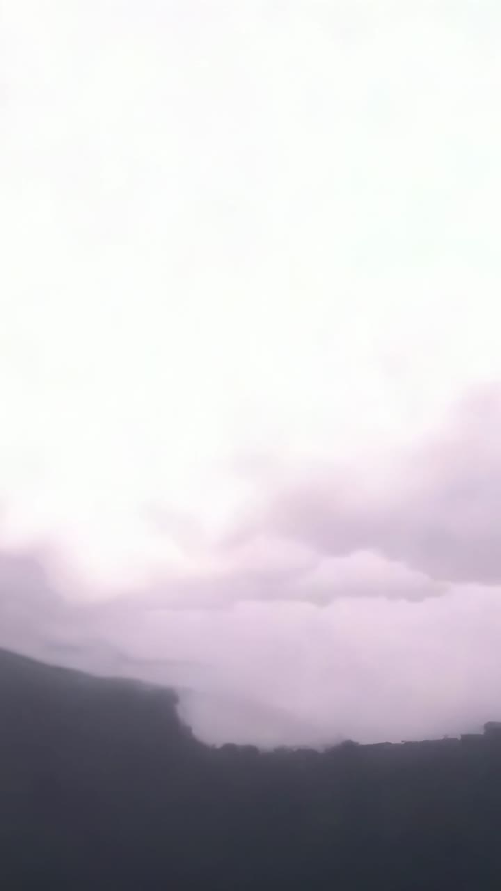 Vertical video: Displaying shelf cloud glowing purple then striking lightning bolts above farmland