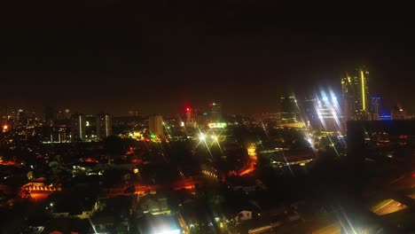Birds-eye-view-of-light-glowing-cityscape-at-night-time-lapse,-light-trails-in-background