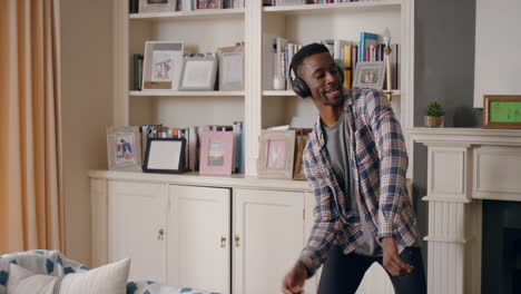 funny african american man dancing at home wearing headphones celebrating success listening to music having fun crazy dance in living room happy lifestyle 4k