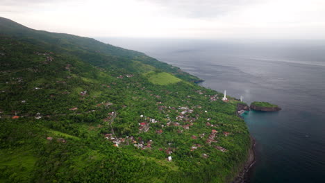 Tropical-forest,-buildings,-ocean-water,-lighthouse-location,-aerial