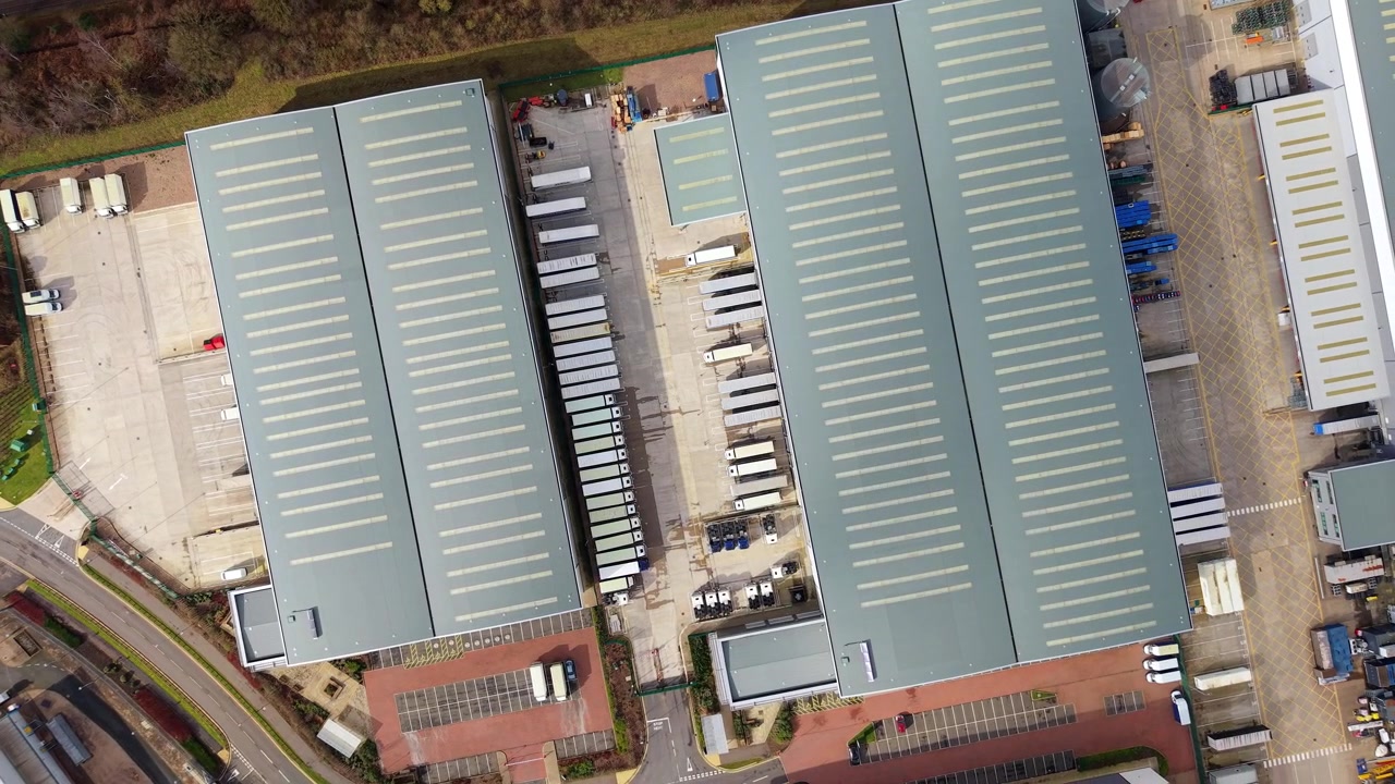 Luftperspektiv af et udstrakt kommercielt logistikområde, der viser massive distributionscentre og parkerede lastbiler i Coleshill, Storbritannien