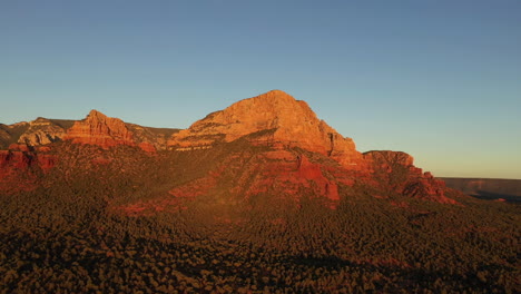 aerial flying backwards over red rocks at sunset