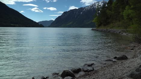 lake surrounded by mountains and its beach next to the hiking trail