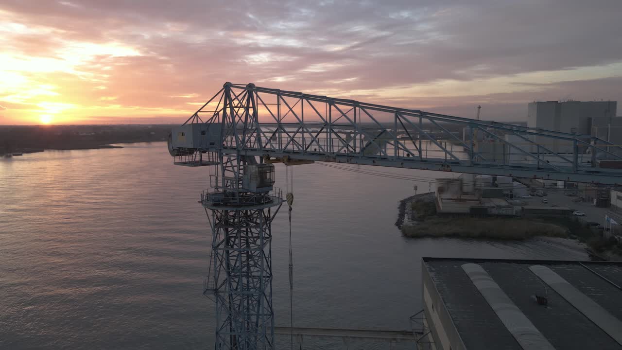 작은 컨테이너 터미널 크레인에 날아다니고 착륙하는 새들의 공중 일몰 전망