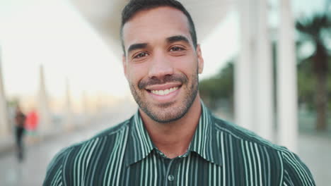 Young-man-smiling-at-the-camera-outdoors.