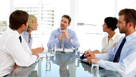 business people listening to manager and taking notes during meeting