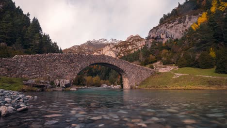 timelapse of bujaruelo valley river and bridge near ordesa national park, aragon, spain o a cloudy fall autumn day