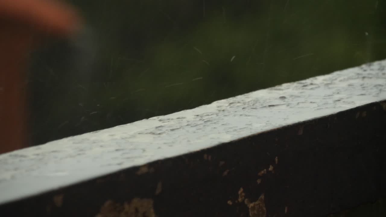Tiny droplets of rain water falling in a splash on an old balcony wall with old paint during a cloudy day in the south of France near Marseille