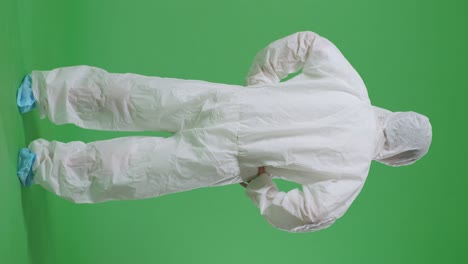 full body back view of asian male scientist putting hands on his hip and looking around on green screen background